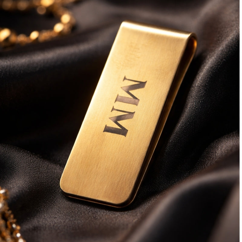 Goudkleurige MM moneyclip van metaal met minimalistisch design op zwarte luxe achtergrond
